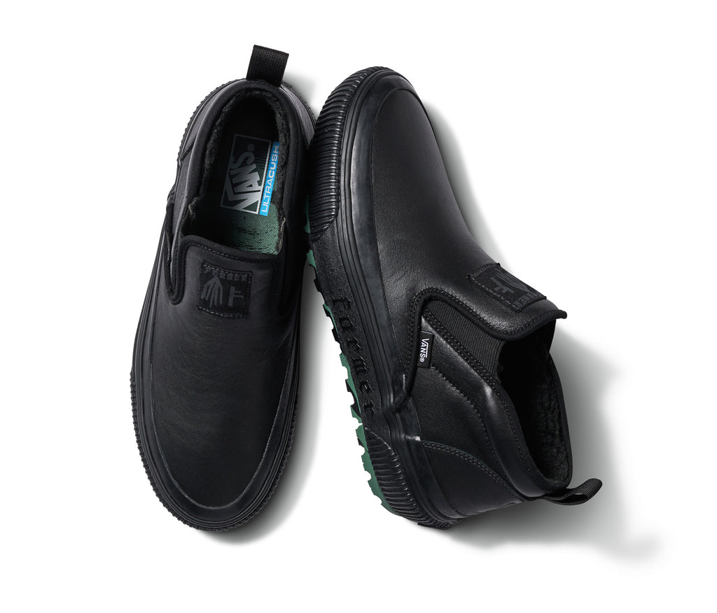 A pair of black VANS X FORMER MID SLIP MTE shoes with green soles.