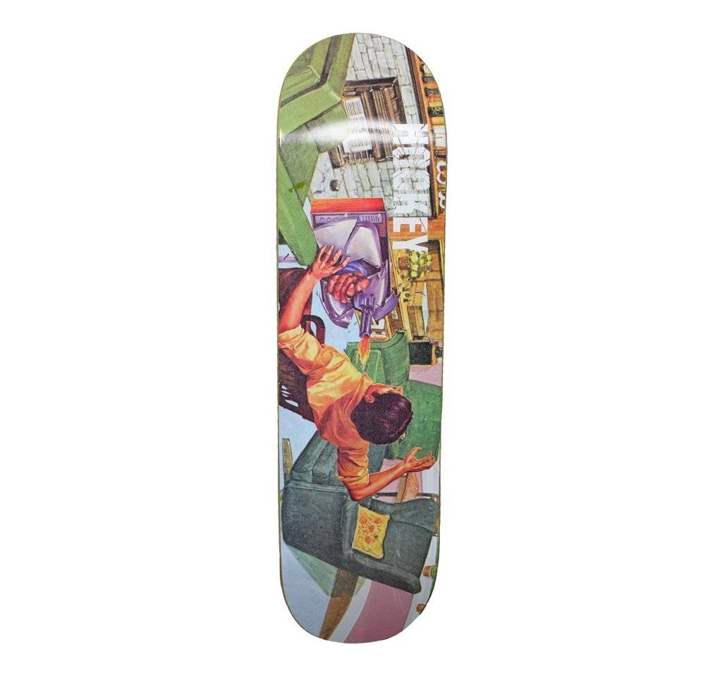The HOCKEY DONOVON ULTRA VIOLET skateboard deck by HOCKEY showcases a vibrant illustration of a person working at a desk with a computer in a home setting, surrounded by household items.