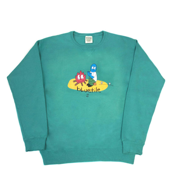 A green BLUETILE CAMP FIRE CREWNECK SPANISH MOSS sweatshirt with a cartoon character on it from Bluetile Skateboards.