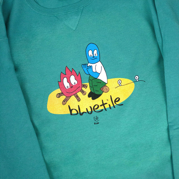A Bluetile Skateboards BLUETILE CAMP FIRE CREWNECK SPANISH MOSS with a cartoon character on it.