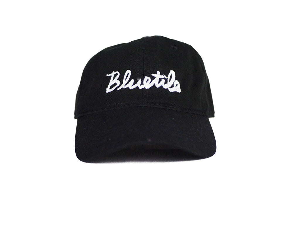 A BLUETILE CURSIVE DAD HAT BLACK with the word 'blues' embroidered on it by Bluetile Skateboards.