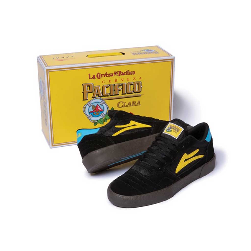 A pair of LAKAI X PACIFICO CAMBRIDGE BLACK/GUM SUEDE sneakers from LAKAI in front of a box.