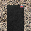a piece of MILES black griptape 9x33 sitting on top of a sidewalk.