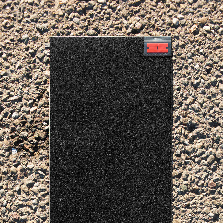 a piece of MILES black griptape 9x33 sitting on top of a sidewalk.