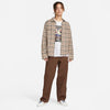 A man standing wearing a plaid jacket and brown NIKE SB KEARNY SKATE CARGO PANT CACAO pants by Nike.