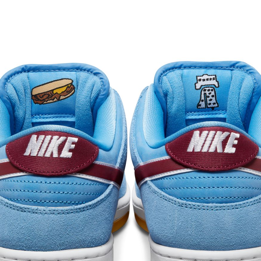 The NIKE SB DUNK LOW PRO "PHILLIES" VALOR BLUE/TEAM MAROON/WHITE features a burger on it.