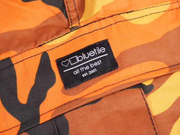 A Bluetile Skateboards orange and black camouflage label on a pair of BLUETILE SURPLUS CARGO PANT ORANGE CAMO pants.