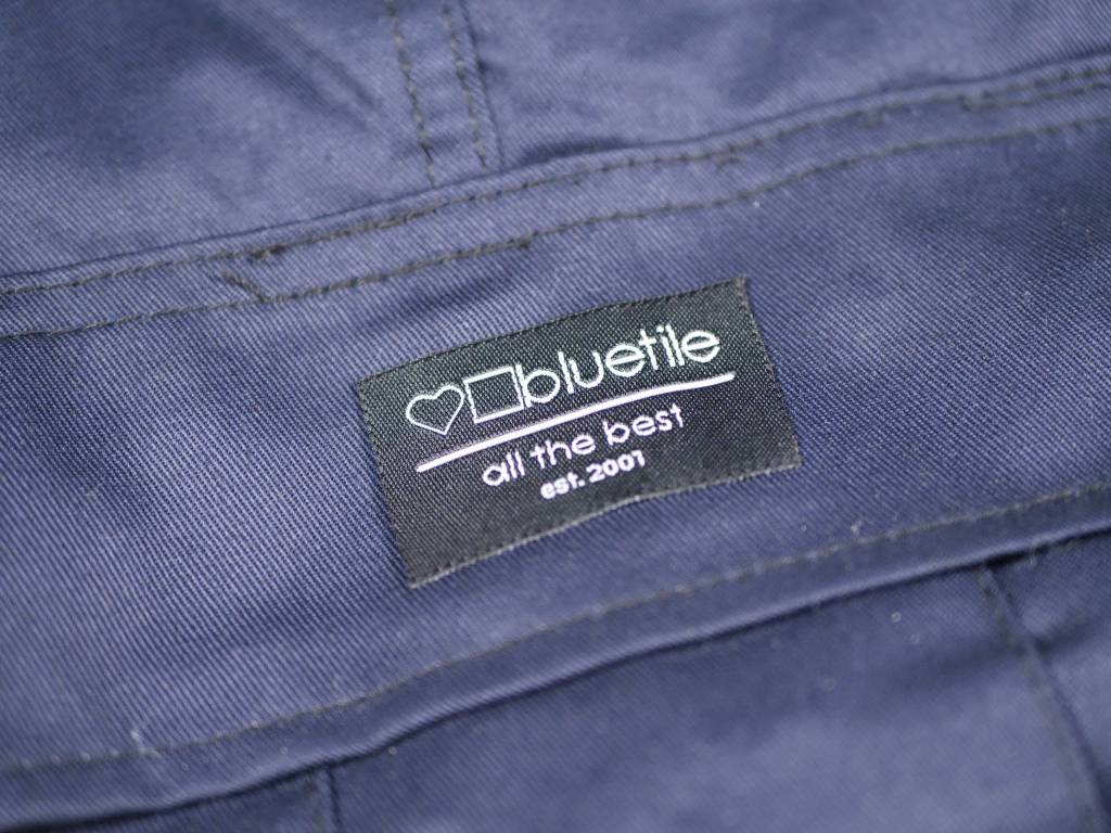 A close up of a label on a BLUETILE SURPLUS CARGO PANT NAVY jacket from Bluetile Skateboards.
