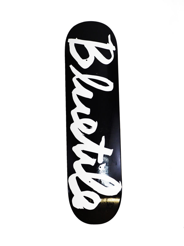 A Bluetile Skateboards skateboard with a BLUETILE CURSIVE LOGO BLACK (VARIOUS SIZES) logo and the word 'blues' written on it.
