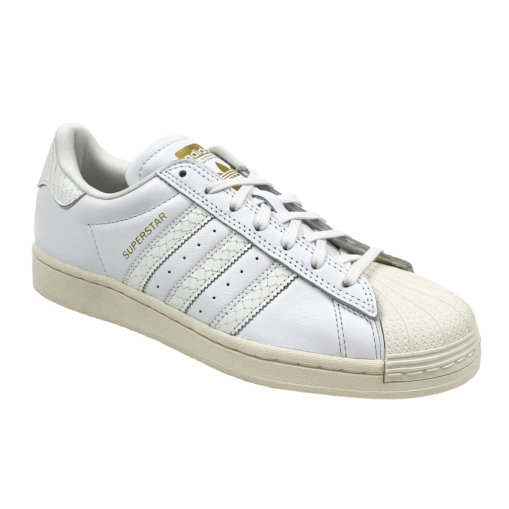 A pair of white and gold ADIDAS SUPERSTAR ADV sneakers from ADIDAS.