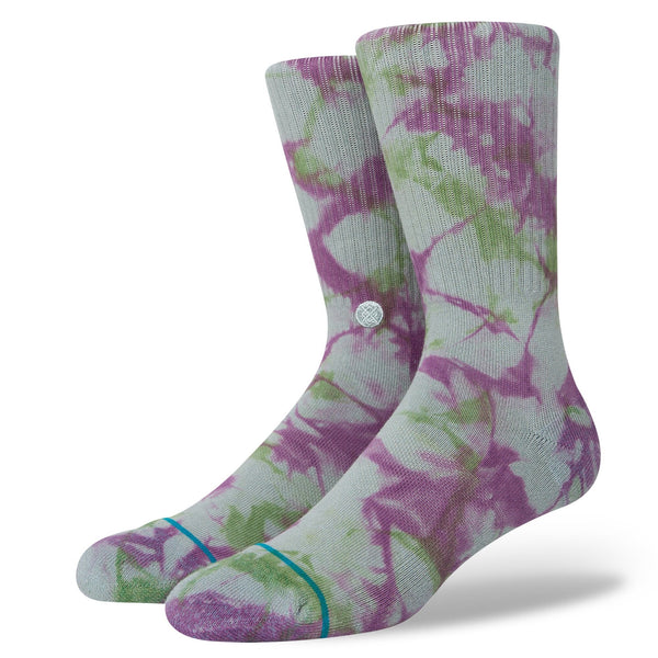A pair of STANCE socks with a green and purple floral pattern displayed against an ELATION BLUE background.