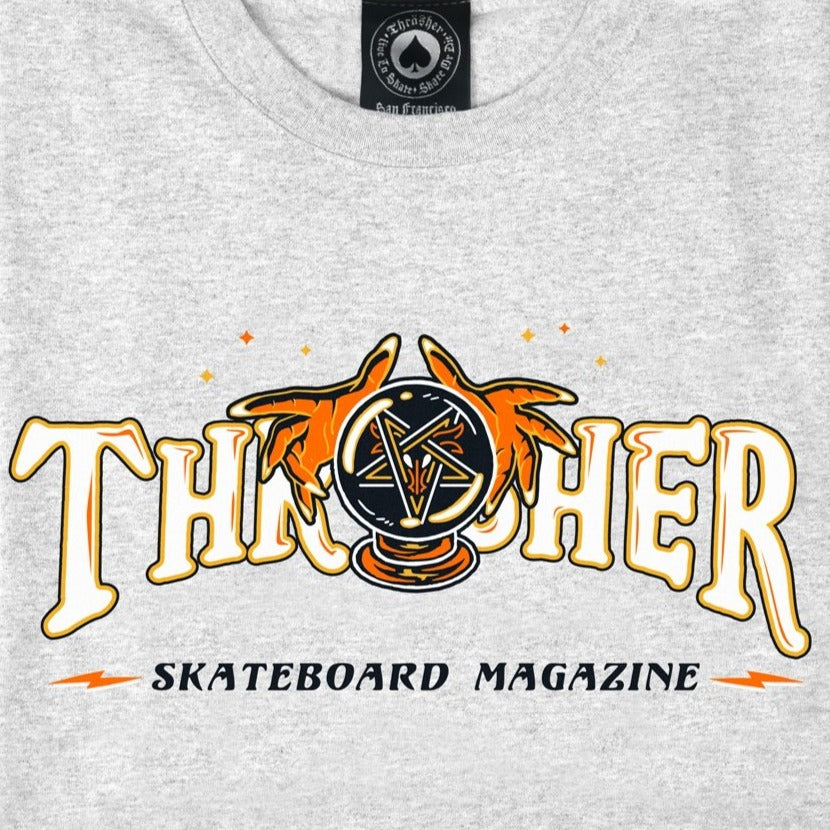 The THRASHER FORTUNE LOGO TEE ASH GREY by THRASHER features the iconic Thrasher Skateboard Magazine logo on an ash grey t-shirt. The design incorporates the word "Thrasher" with stylized hands surrounding a pentagram logo below, making it an ideal choice for skate enthusiasts.