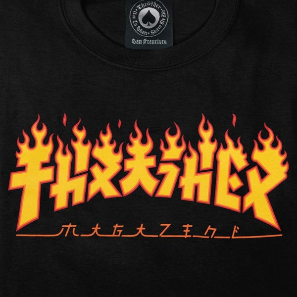 The THRASHER GODZILLA FLAME TEE in black features stylized orange and yellow flaming text and characters printed in the center, with "hydraseek" written prominently along with additional characters below it, evoking a GODZILLA rampage.