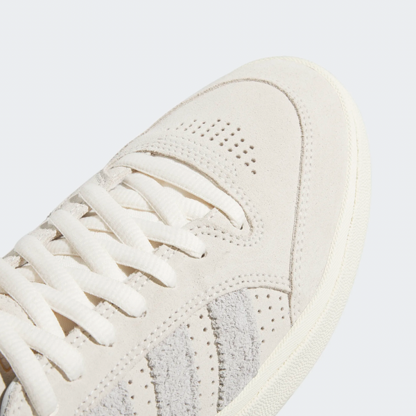 A close up of an ADIDAS TYSHAWN LOW CHALK WHITE / GREY ONE / CREAM WHITE sneaker with white laces.