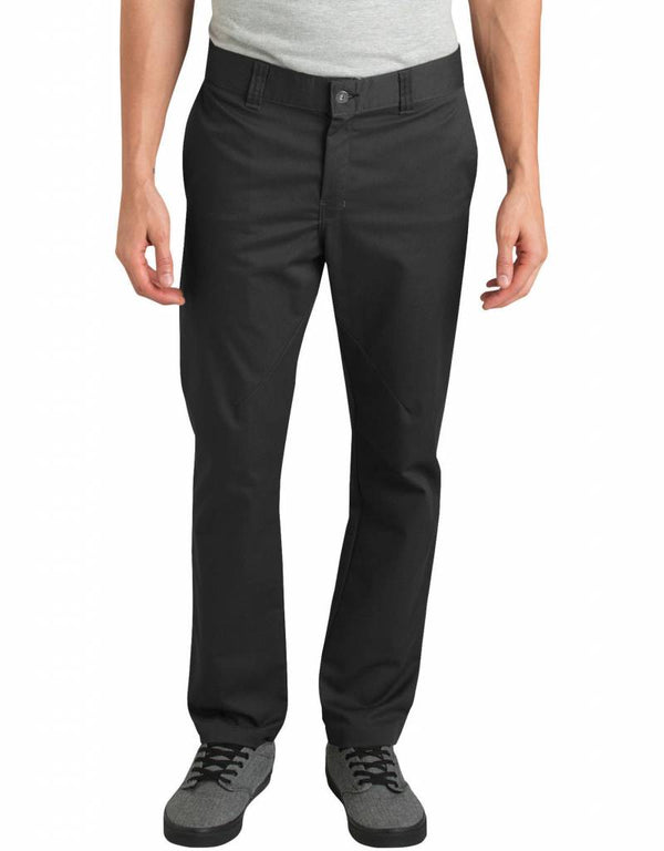 A man stands with arms relaxed, wearing a light gray t-shirt, DICKIES '67 Twill Pant with Pivot-Tek in black for ergonomic comfort, and gray sneakers; visible from shoulders to feet.